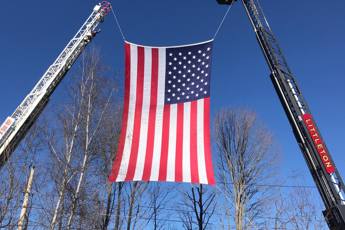American flag displayed between two firetruck ladders